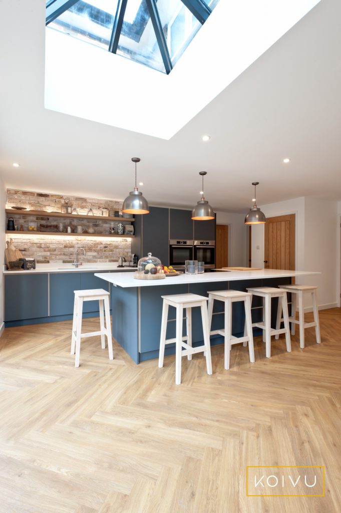 A dark grey plywood kitchen fitted in Tonbridge by Koivu. Design includes a large island housing integrated hob and family-sized breakfast bar.
