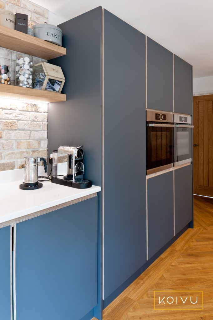 A dark grey plywood kitchen fitted in Tonbridge by Koivu. A view of the open shelving meeting the floor to ceiling units. Beautiful plywood detailing. By Koivu