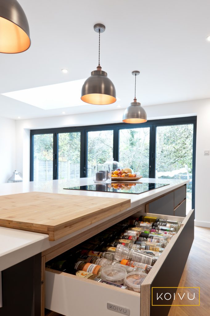 Interior details. See inside the spices drawer in this large grey island with a white countertop. Designed and made by Koivu.