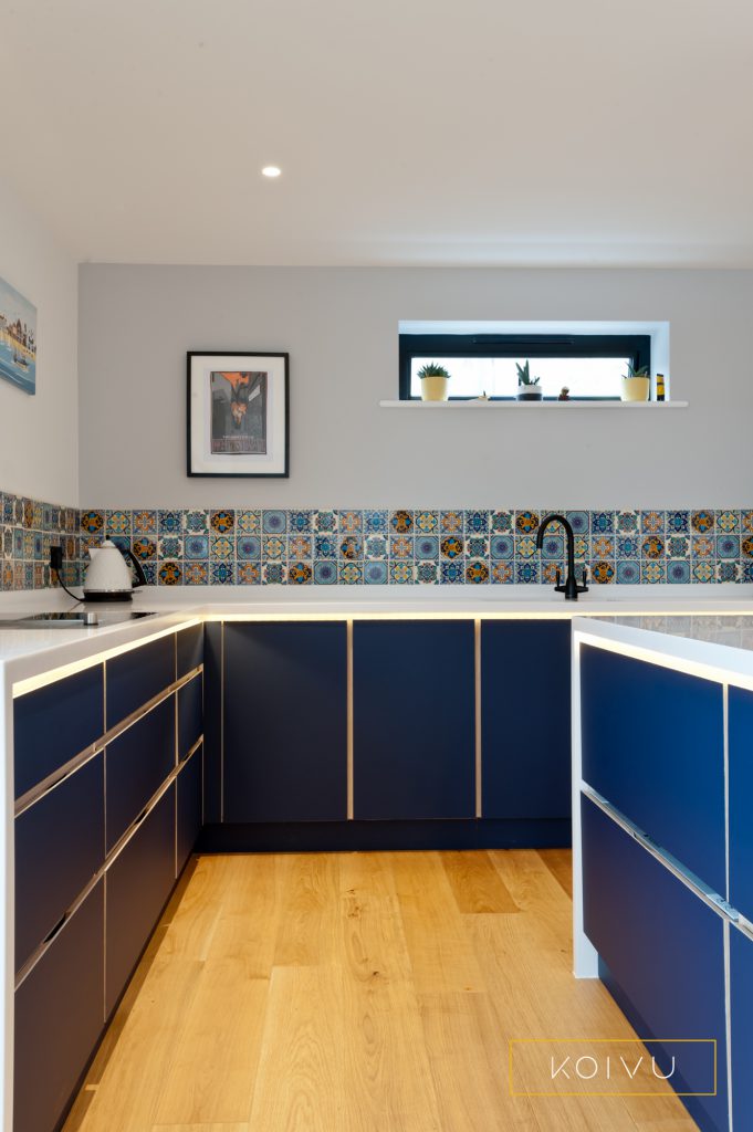 Dark blue, 70s style kitchen with low level units and deep refrigerator drawers.