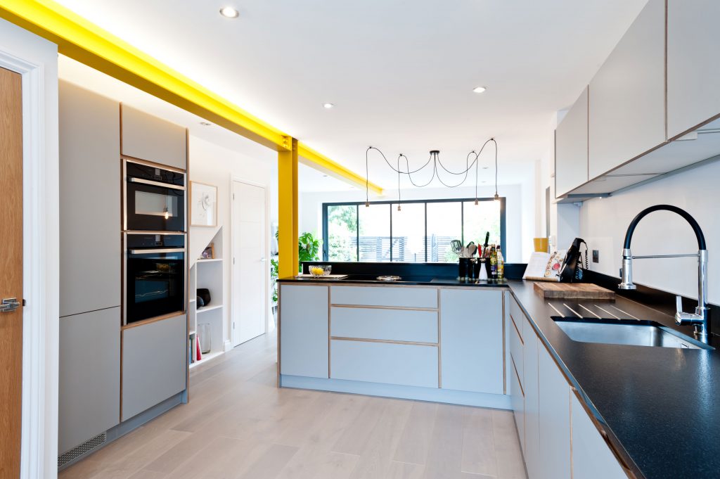Light grey kitchen with black worktops and yellow accents. Designed by Koivu.
