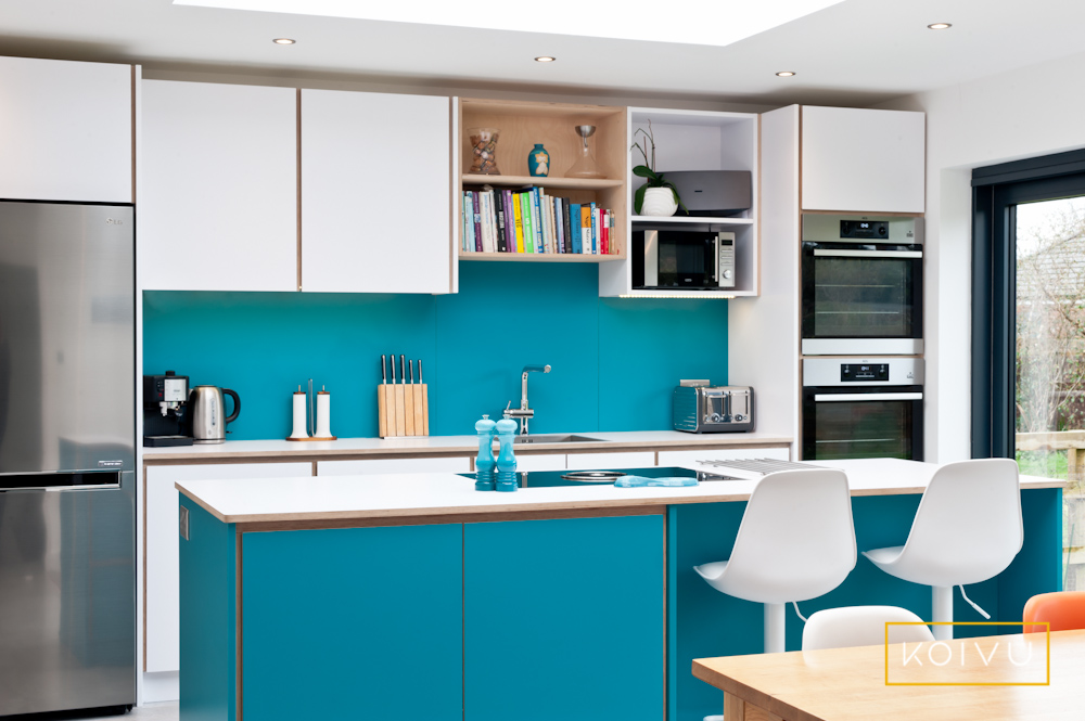 A Warwickshire kitchen by Koivu. White units along the back wall with bespoke designed turquoise island housing a hob. 