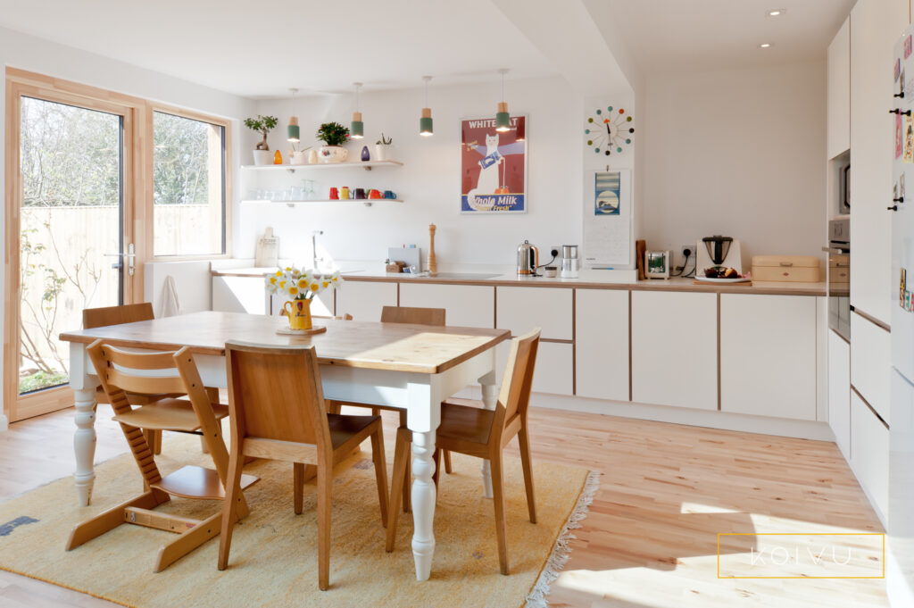 White kitchen in plywood with space for dining table and view to garden. By Koivu.