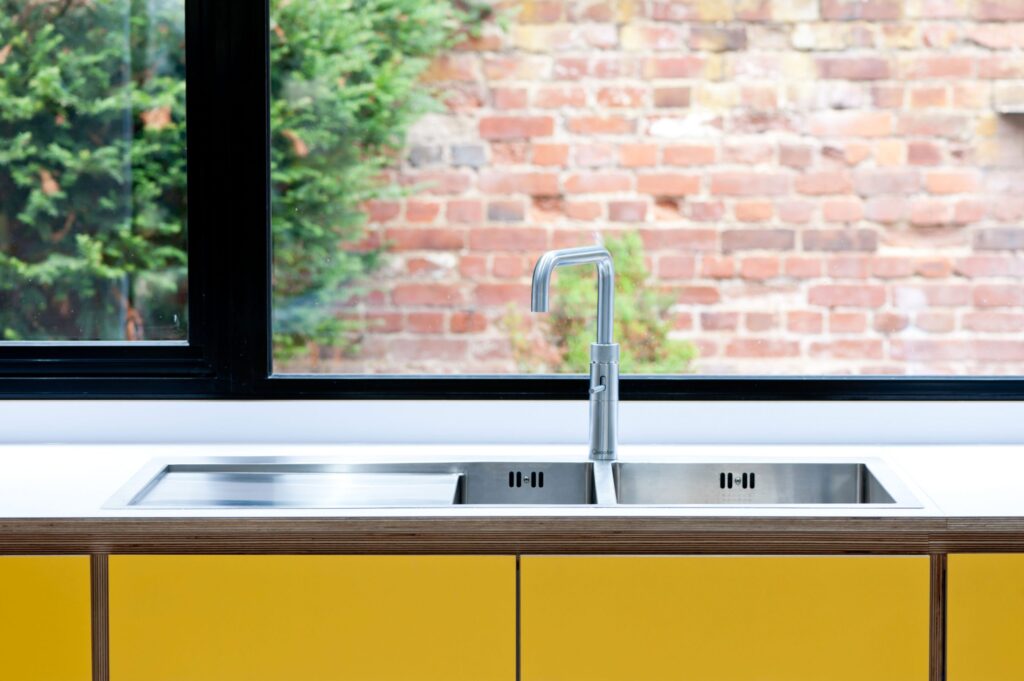 Tap over sink in front of window in spectrum yellow kitchen