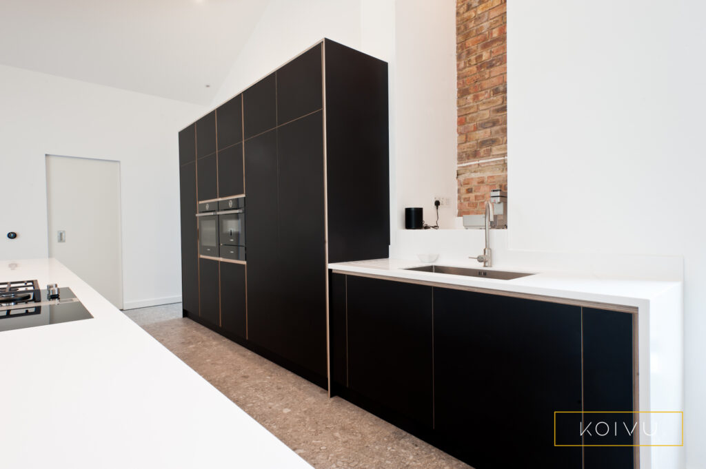 Tall black kitchen units with white countertops in this large kitchen extension.
