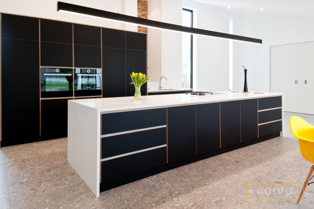Plywood detailing and long lines in this sleek black kitchen in Leatherhead. By Koivu.