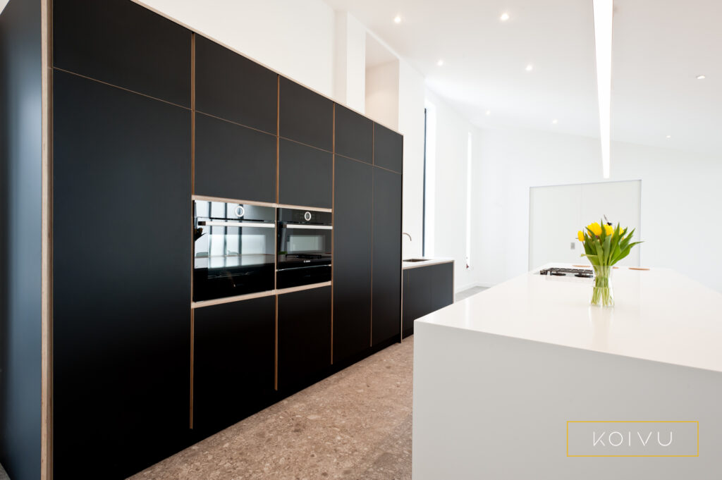 Tall black cabinets made from sustainable birch plywood. Streamlined minimalist kitchen designed by Koivu.