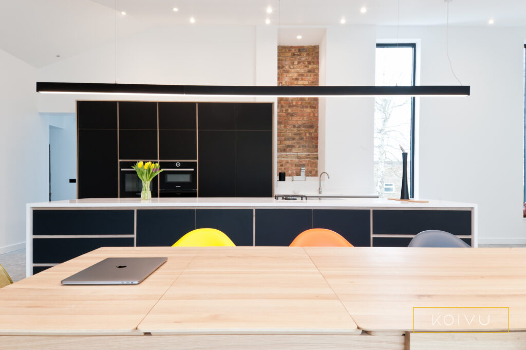 Minimalist black kitchen design. Beautiful plywood lines, matt black cabinet doors and white worktops.