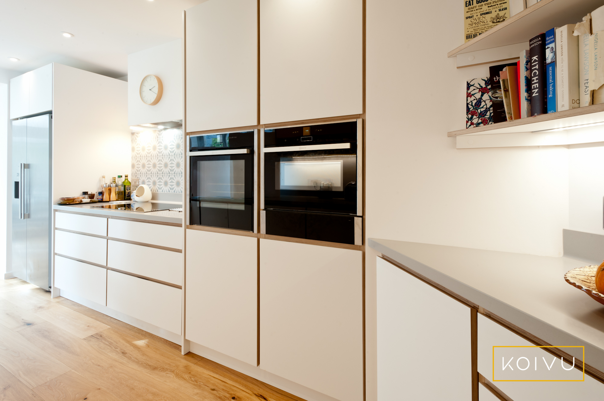 Plywood kitchen from Koivu with side by side oven housing, American-style fridge freezer and open kitchen shelving.