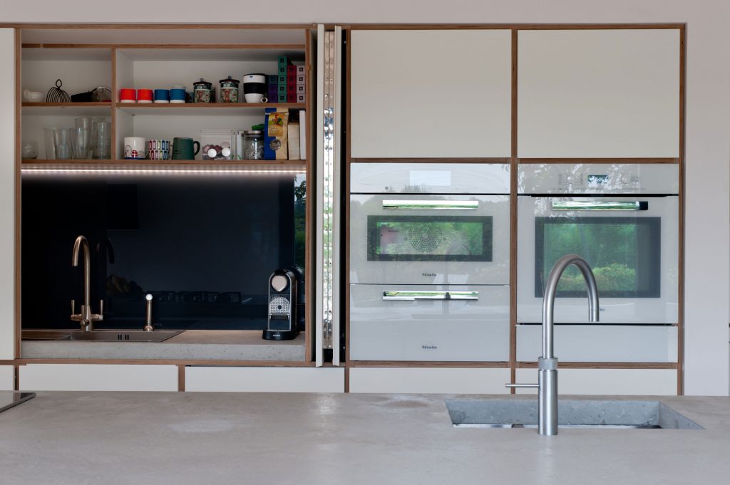 Butler's cupboard with doors open in a white plywood kitchen designed by Koivu.