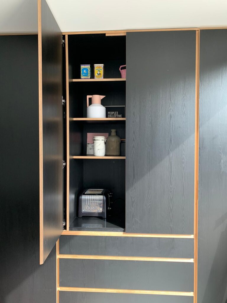 A picture of a bespoke designed black plywood Butler's Cupboard with one of the doors open to show the flexibility of the design