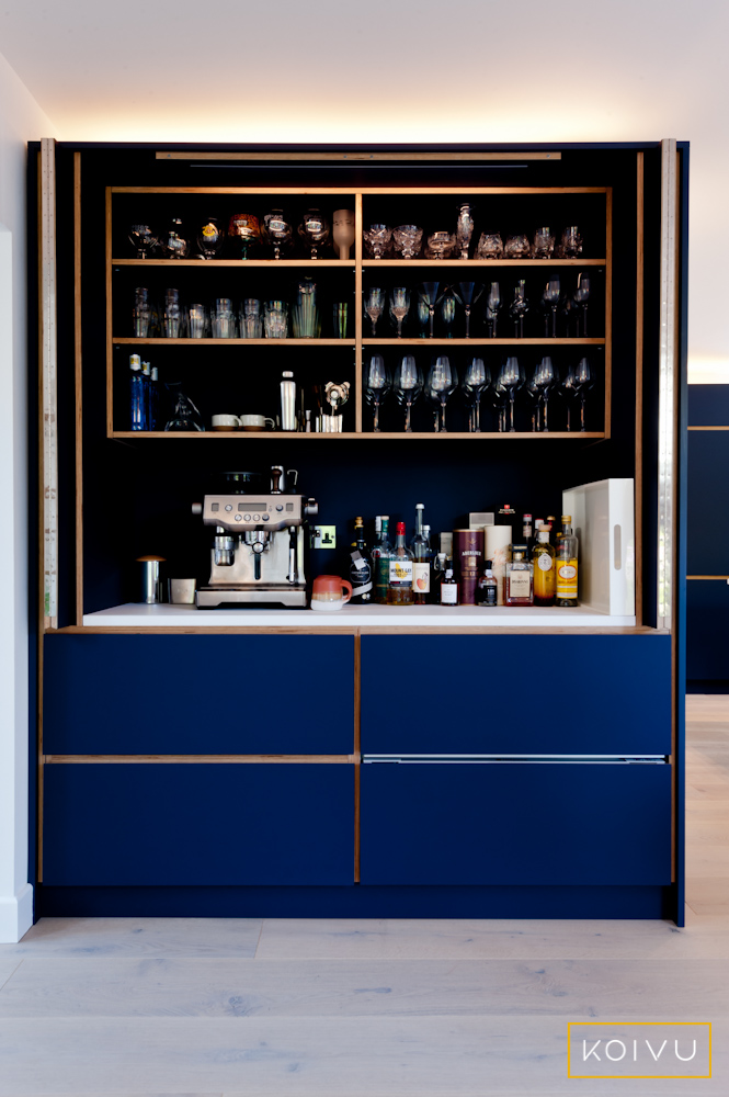 Open view of plywood butler's cupboard showing shelves with glasses, coffee machine and spirits. Everything can be hidden from view when not in use.