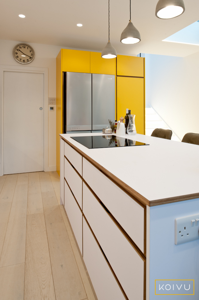 White and yellow kitchen with island and large American style fridge / freezer. By Koivu.