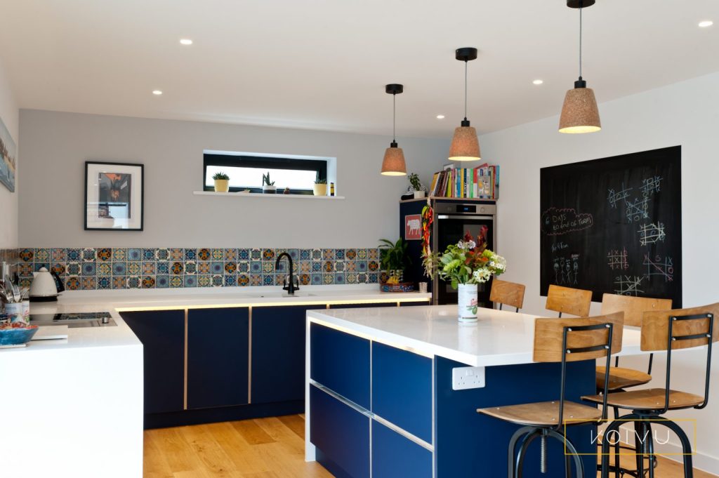 Dark blue kitchen including kitchen island with seating. The large drawers in the kitchen island are deep fridge drawers. 