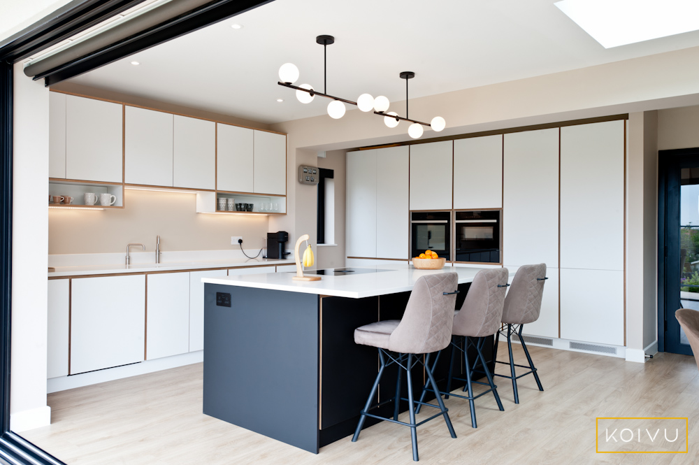 White and black kitchen - showing higher height cabinets on the back wall. These have been used to maximise storage in this L-shaped kitchen with island. 