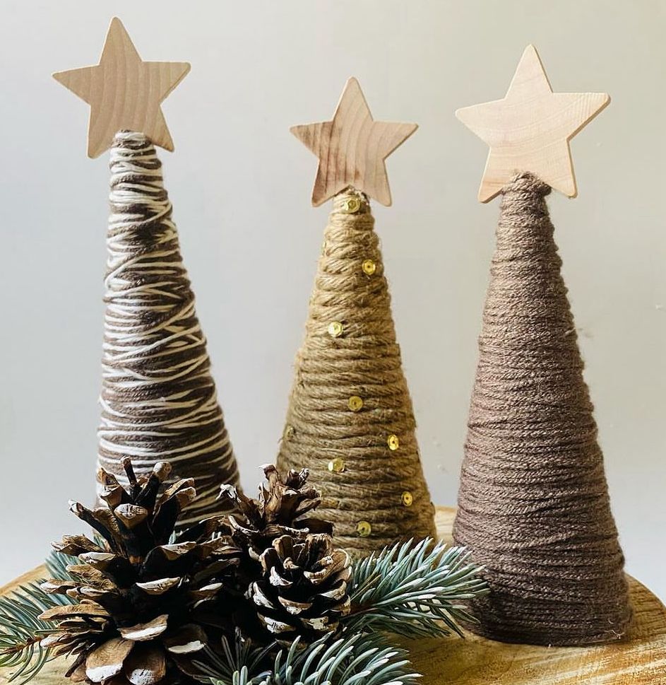 Cone-shaped Christmas trees covered in neutral yarn and gems for an eco-friendly decoration.